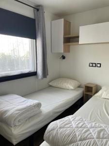 twee bedden in een kamer met een raam bij Mobilhome Ck135 Siblu Les Charmettes in Les Mathes