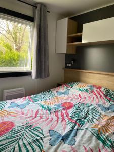 een bed met een kleurrijk dekbed in een slaapkamer bij Mobilhome Ck135 Siblu Les Charmettes in Les Mathes