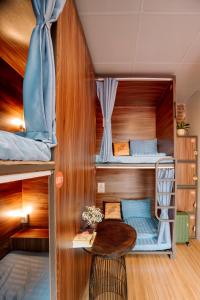 ニンビンにあるWafami Hostel Ninh Binhの二段ベッド2台とテーブルが備わる客室です。