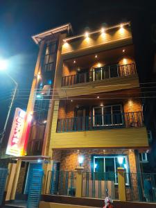 a tall yellow building with a balcony at night at Uttara Residency in Siliguri
