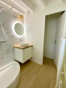 W białej łazience znajduje się umywalka i lustro. w obiekcie Maison proche centre, gare, aux Sables d'olonne w mieście Les Sables-dʼOlonne