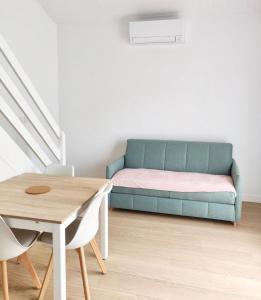 een woonkamer met een blauwe bank en een tafel bij Maison proche centre, gare, aux Sables d'olonne in Les Sables-dʼOlonne