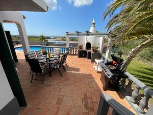 a patio with a table and chairs and a pool at Villa Monte Alegrete with sea view in Santa Bárbara de Nexe