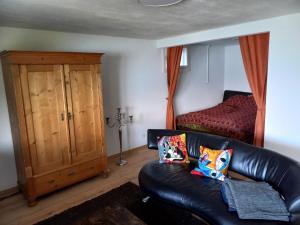 a living room with a leather couch and a bed at Seeblick in Aeschlen