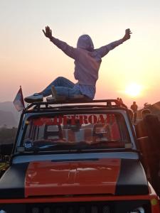 a person is sitting on the roof of a car at jeep tour bali in Kintamani