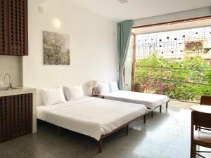 2 camas en una habitación con ventana en LaRose Cafe I Bed & Breakfast, en Quy Nhon