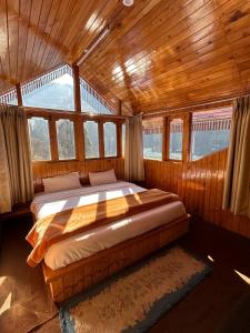 THE OFFBEAT CHALET في Jibhi: غرفة نوم مع سرير في غرفة مع نوافذ