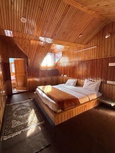 een slaapkamer met een bed in een houten kamer bij THE OFFBEAT CHALET in Jibhi