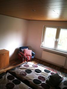 a bedroom with a bed and a chair and a window at Ferienwohnung mit Balkon 1.OG in Neustadt bei Coburg