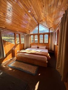 ein Schlafzimmer mit einem Bett in einem Zimmer mit Fenstern in der Unterkunft THE OFFBEAT CHALET in Jibhi