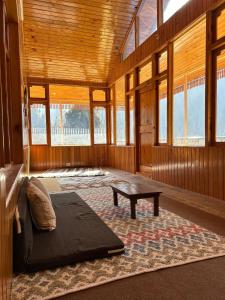 Großes Zimmer mit einem Bett und einem Tisch. in der Unterkunft THE OFFBEAT CHALET in Jibhi