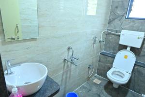 een badkamer met een wastafel, een toilet en een spiegel bij Hotel Mint Leaf in Kāgal