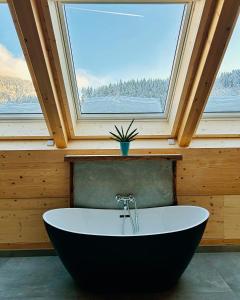 uma grande banheira num quarto com uma janela em Ferienwohnung im Loft-Style mit Sauna im historischen Schwarzwaldhof em Simonswald