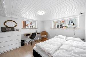 a white bedroom with a bed and a desk at Nyd den skønne natur ved hav og fjord in Thyborøn