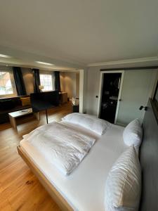 Cama blanca grande en habitación con suelo de madera en Hotel Lamm en Baiersbronn