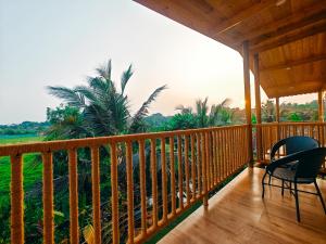 a porch with chairs and a view of a palm tree at The Lazy Cabanas in Candolim