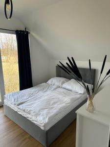 Domy przy Spokojnej في يانتار: غرفة نوم بسرير و مزهرية بها نبات