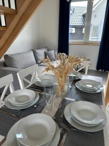Domy przy Spokojnej في يانتار: طاولة طعام مع أطباق وكراسي بيضاء