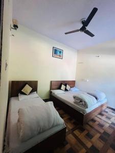 two beds in a room with a ceiling fan at Priya Hotel, Sitapur in Trijugi Nārāyan