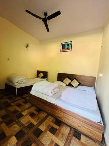 two beds in a room with a ceiling fan at Priya Hotel, Sitapur in Trijugi Nārāyan