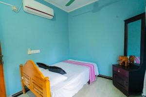 ein blaues Schlafzimmer mit einem Bett und einer Kommode in der Unterkunft Passi CK Homestay in Pasikuda