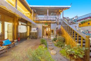 丽江GeGeHouse - Lijiang Old Town的一座古老的建筑,拥有种有植物和楼梯的庭院