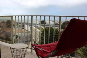 une chaise rouge assise sur un balcon avec une table dans l'établissement Appartement vue panoramique mer, prêt de vélos, WIFI, à Quiberon