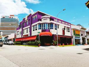 ein lila-weißes Gebäude in einer Stadtstraße in der Unterkunft Sandpiper Hotel Singapore in Singapur