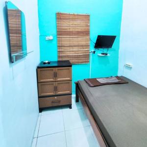 Habitación con cama, escritorio y TV. en Rumah Teman Homestay, en Semarang