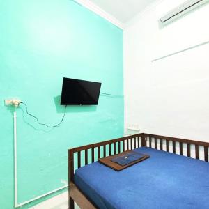 um quarto com uma cama e uma televisão na parede em Rumah Teman Homestay em Semarang