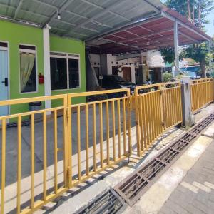 uma cerca amarela em frente a um edifício verde em Rumah Teman Homestay em Semarang
