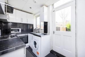 a kitchen with a white door and a washing machine at Heads on Bed - Dagenham 3Bedrooms House walk to Station with Parking in Dagenham