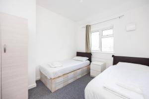 sypialnia z 2 łóżkami i oknem w obiekcie Heads on Bed - Dagenham 3Bedrooms House walk to Station with Parking w mieście Dagenham