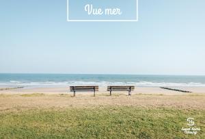 two benches sitting on the beach near the ocean at Sweet Home Cabourg Hôtel et gîtes in Cabourg