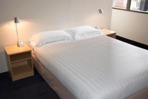 1 dormitorio con 1 cama blanca grande y 2 mesitas de noche en Siesta Sydney en Sídney