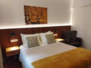 um quarto de hotel com uma cama e uma cadeira em Casa do Rio nas Termas de São Pedro do Sul
