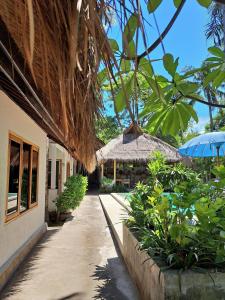 a walkway next to a building with a straw umbrella at Eden Eco Resort in Gili Trawangan