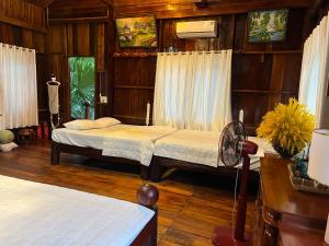 a bedroom with two beds and a fan at Paradise on the Tree in Cat Tien