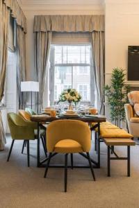 een eetkamer met een tafel en gele stoelen bij Harley Street Spectacular Suites with High Ceilings, High Luxury in Londen