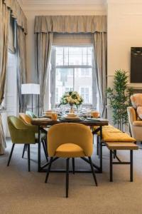 a dining room with a table and yellow chairs at Harley Street Spectacular Suites with High Ceilings, High Luxury in London