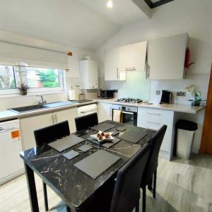 cocina con mesa con sillas y encimera en The Old Smiddy Cottage and Apartment, en Balloch