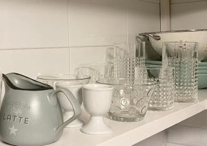 a shelf with various glass cups and a pitcher at Vivienda vacacional el grillo feliz in Tegueste