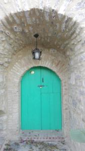 eine grüne Tür in einer Steinmauer mit einem Kronleuchter in der Unterkunft Giro di vite in Rocca Imperiale