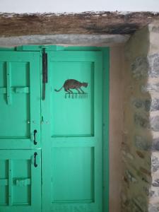 un gato corre por una puerta verde en Giro di vite, en Rocca Imperiale