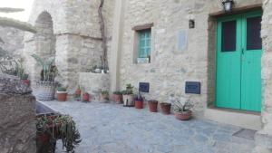 Ein Gebäude mit einer grünen Tür und einem Haufen Topfpflanzen. in der Unterkunft Giro di vite in Rocca Imperiale
