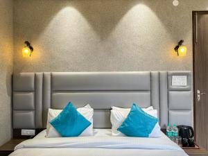 a bedroom with a bed with blue pillows at Hotel The Mantra , Haridwar in Haridwār