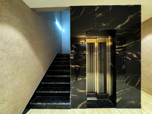 einen Flur mit einer Treppe mit schwarzem Marmor in der Unterkunft Hotel The Mantra , Haridwar in Haridwar