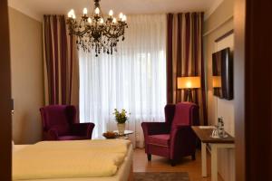 a hotel room with a bed and chairs and a chandelier at Hotel Waldperle in Göhren