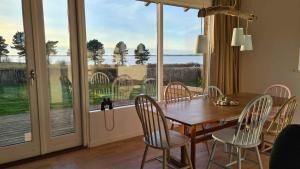 a dining room with a table and chairs and a large window at Sunset Lodge With View Over Grnsund in Stubbekøbing