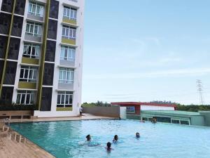 a group of people in a swimming pool next to a building at LV13 PoolView Kuantan by Vhomestay in Kuantan